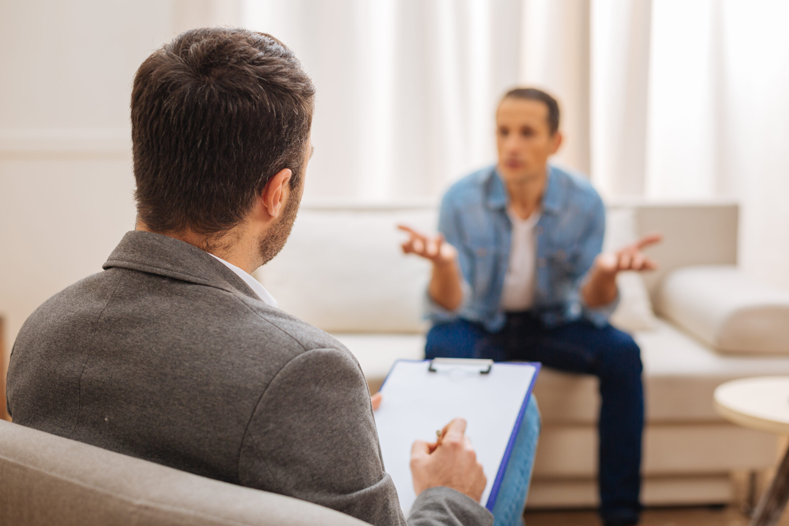 Male serious psychologist listening to his patient